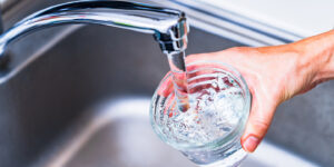 Glas unter laufendem Wasserhahn.