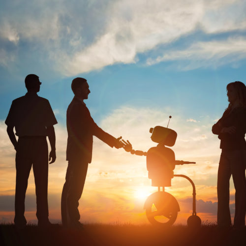 Menschen mit Roboter vor Sonnenuntergang